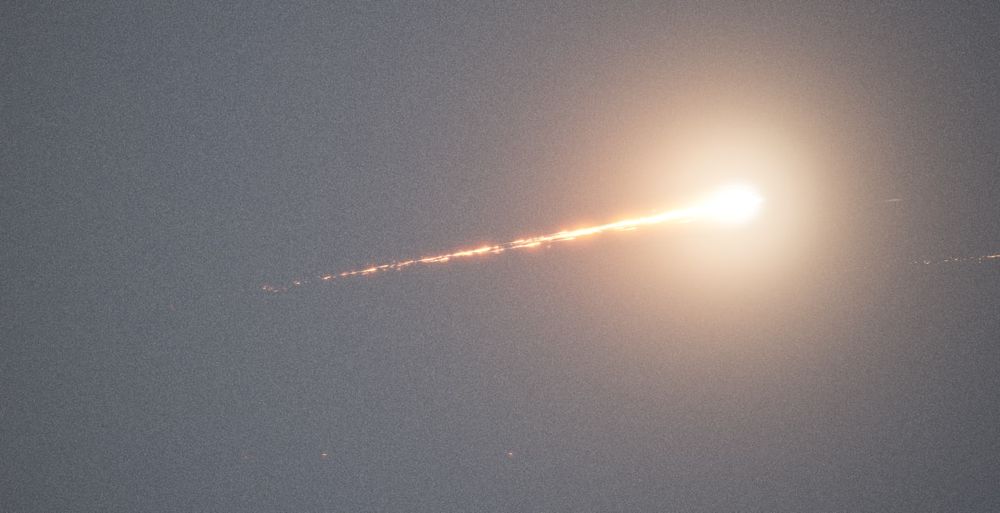 A screenshot from a videogame showing a reentry trail effect. An object is entering the atmosphere and burning up, leaving a bright trail of debris across the sky.