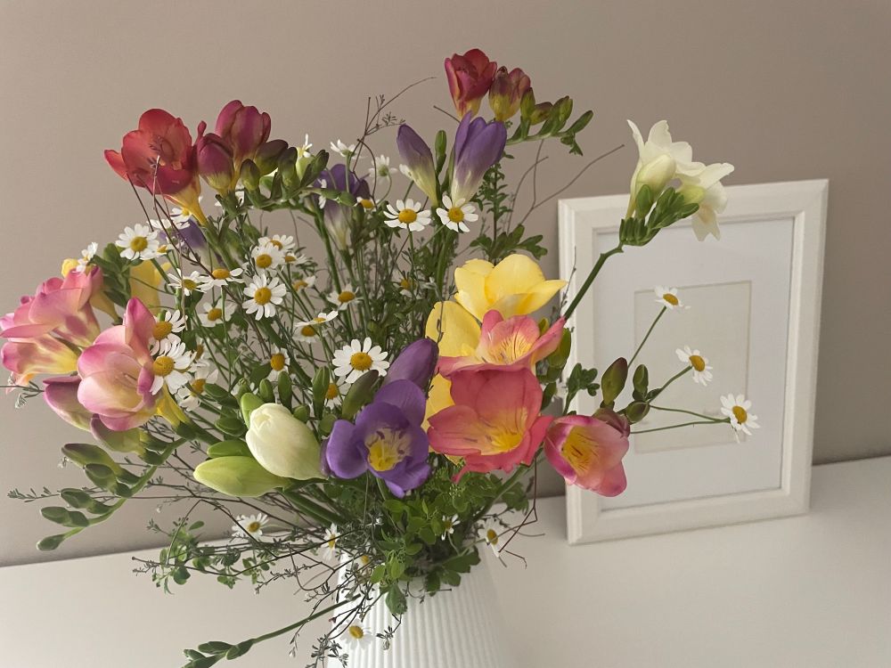 Strauss mit Blumen in gelb, orange, weiß, rot und lila, u. a. Freesien.