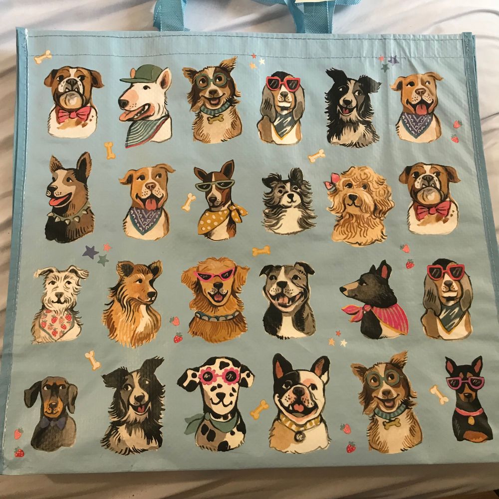 A blue bag with different dog breed faces on it. Some of them are wearing sunglasses. 