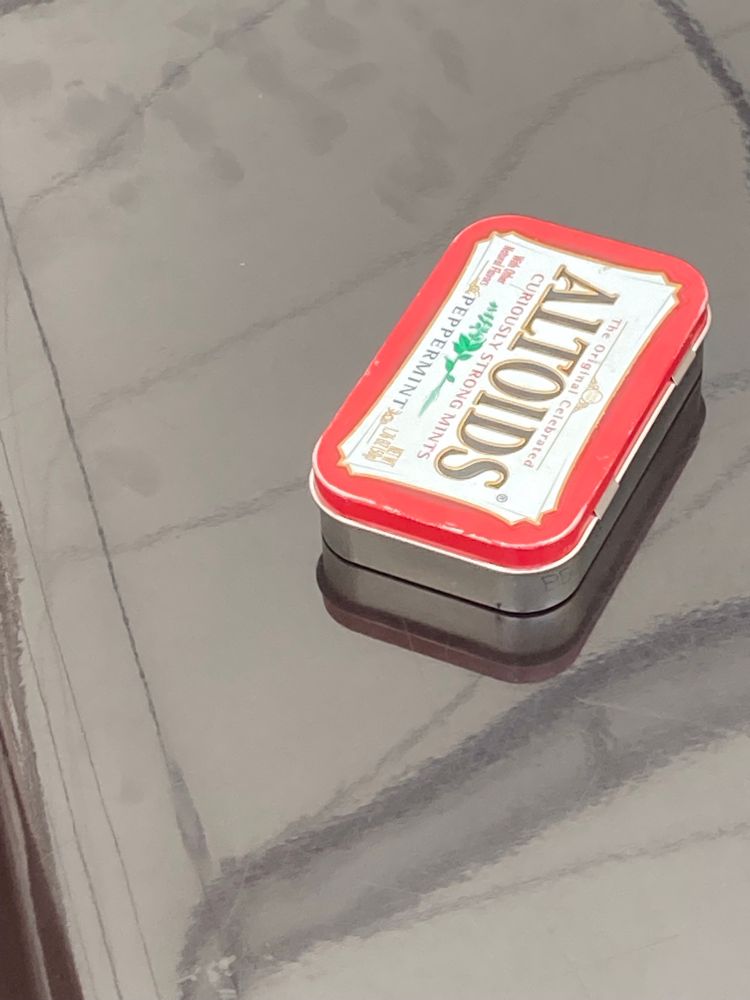 Box of Altoids on a tin-grey reflective table top