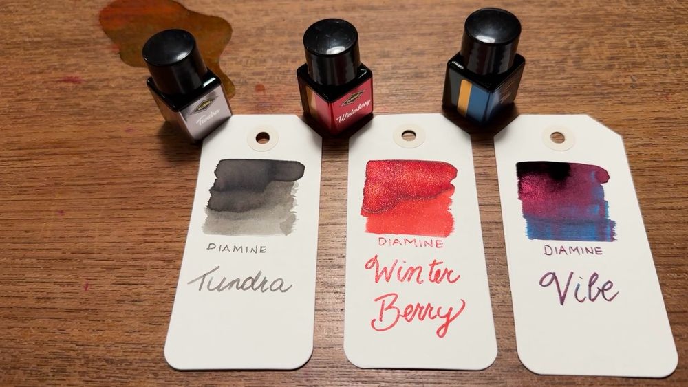 Three bottle of ink, the paper tags. One has a grey swatch and says Tundra, one has a red swatch and says Winter Berry and the third has a dark blue, violet and pink swatch and says Vibe