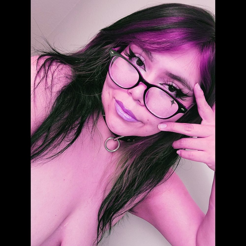 Pink color edited selfie of me with makeup, glasses, and a collar on. No direct nudity; but I was naked. Saggy underboobs and bit of armpit hair sticking out as my arm was up making a lazy peace sign. 