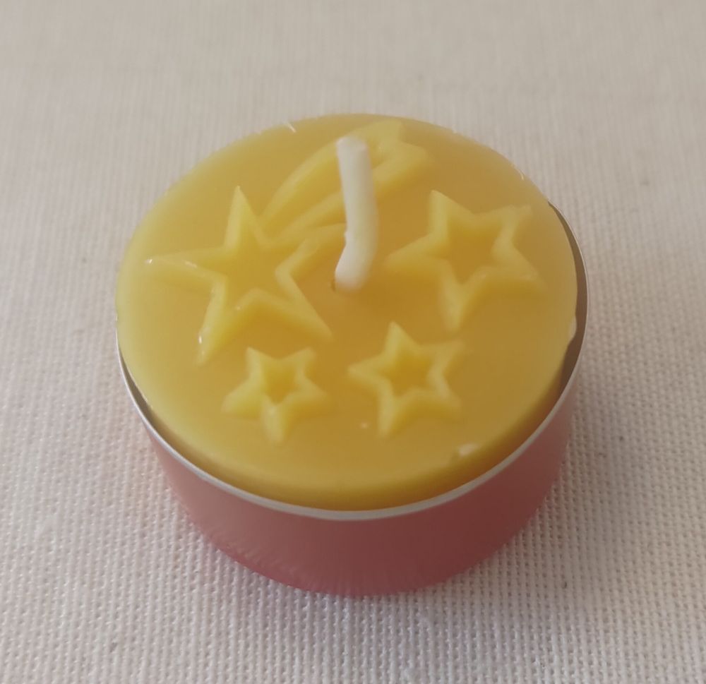 Bienenwachs-Teelicht. In die Oberfläche sind ein Komet und 3 Sterne eingeprägt.