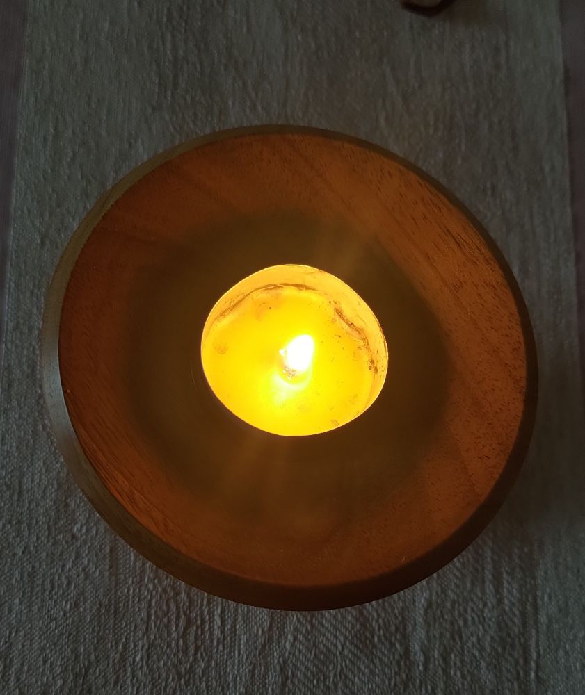 Ein brennendes Teelicht in einem Holzleuchter.
