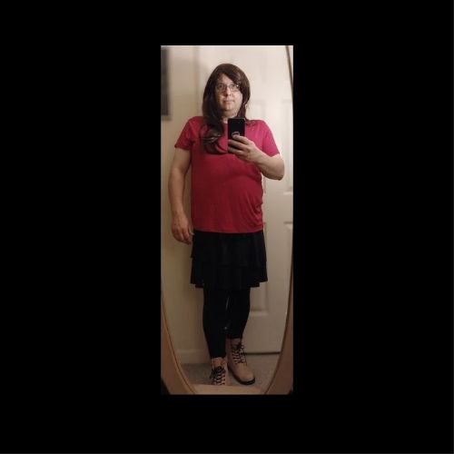 Me in a brown wig, pink shirt, black dress, black leggings and light pink boots.