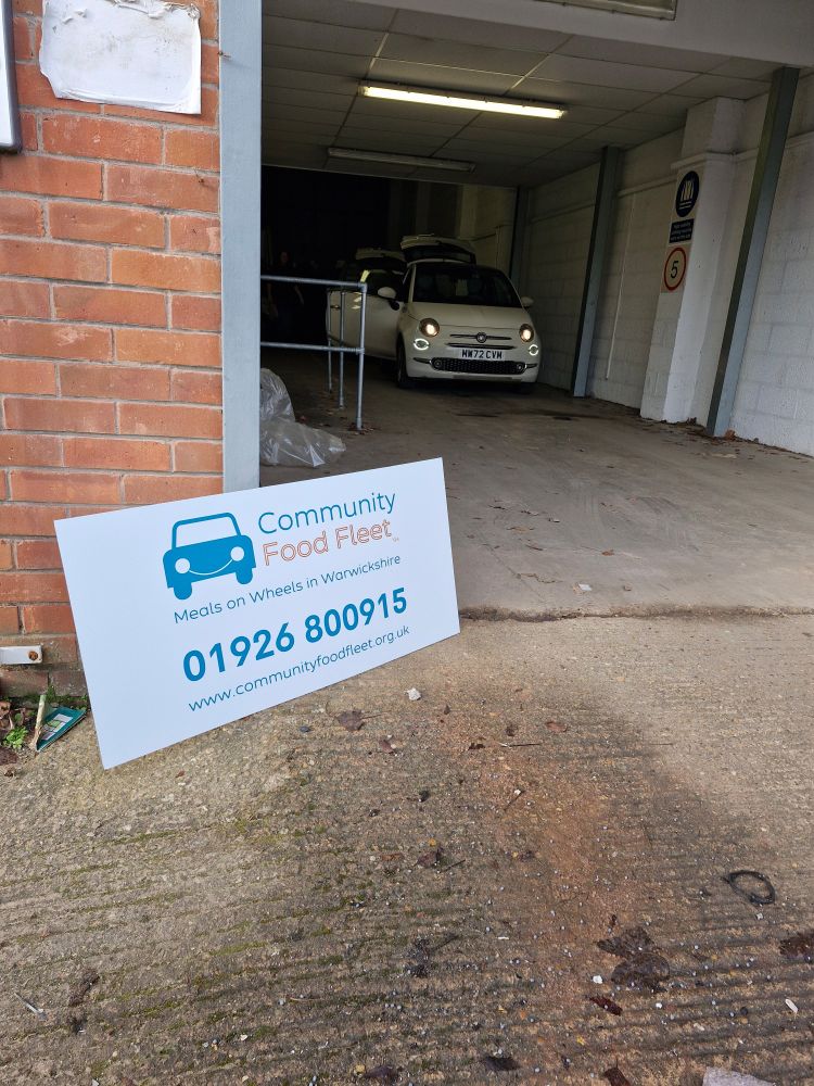 Photo shows the Community Food Fleet signage at WRCC's Meals on Wheels distribution hub in Leamington Spa. The sign shows the number for this service which is 01926 800915.