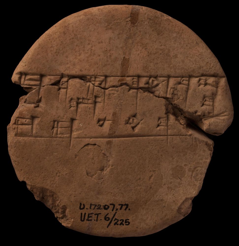 Circular clay tablet with three lines of cuneiform text across the middle. Modern ID in ink at the bottom reads UET 6/225