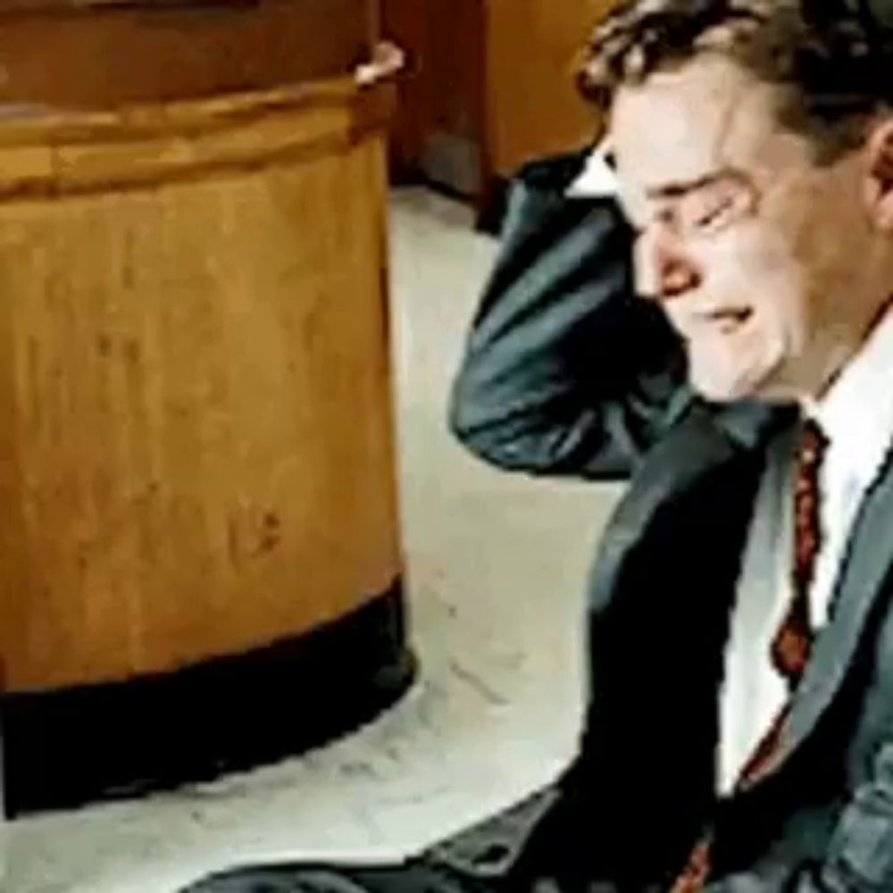 a man in a suit and tie is sitting on the floor .