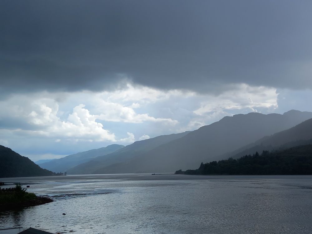 Photograph of a Scottish Loch, with dark and towering clouds building up. 
