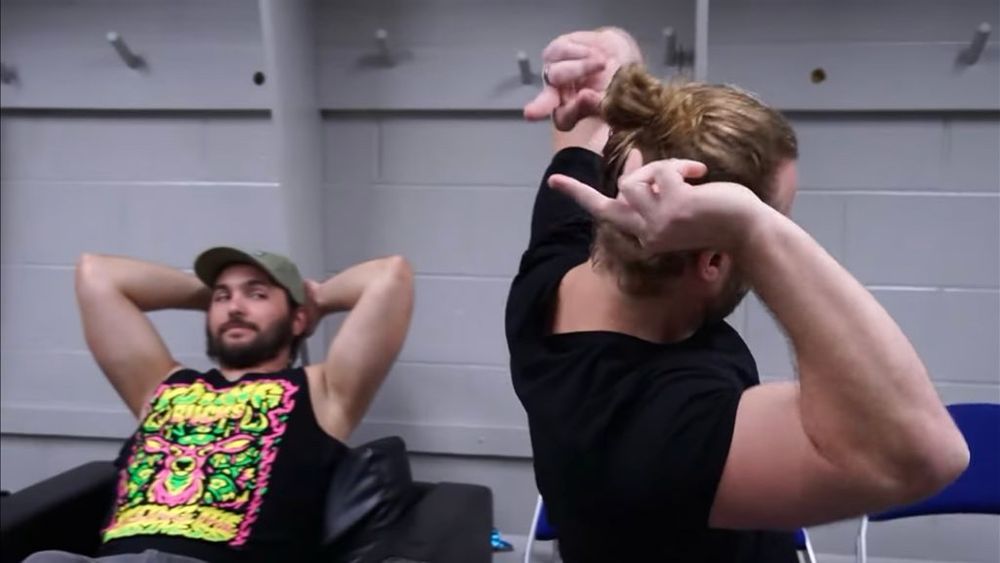 nick jackson (left) watching hangman (right) reaching his hands behind his head and doing the middle finger with both hands 