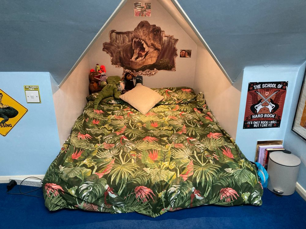 A bed cave sporting green and pink jungle-themed bedding. 