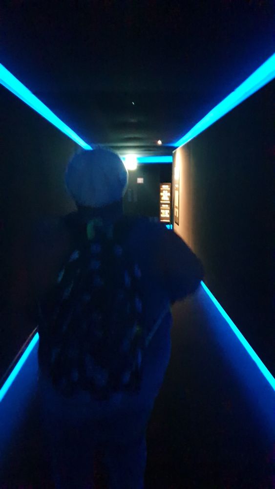 Photo of a hallway with blue lights and a person walking down it