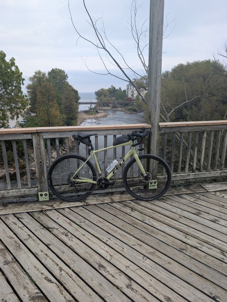 Bicycle sitting on a bridge, with a small river beneath it