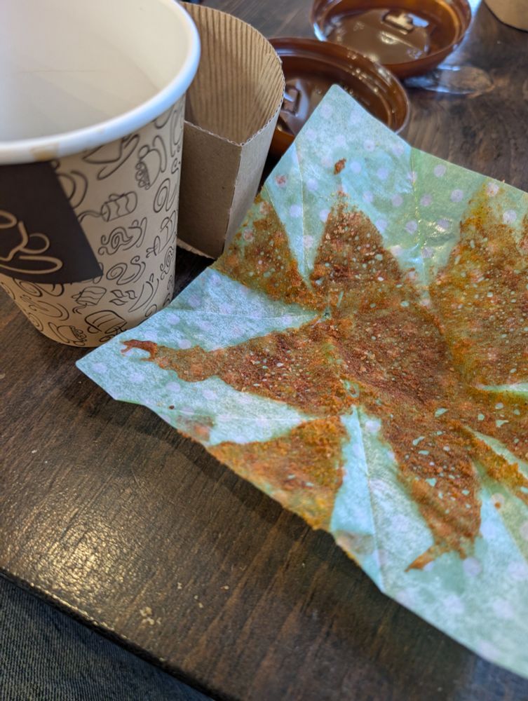 Paper coffee cup, almost empty, and a muffin wrapper