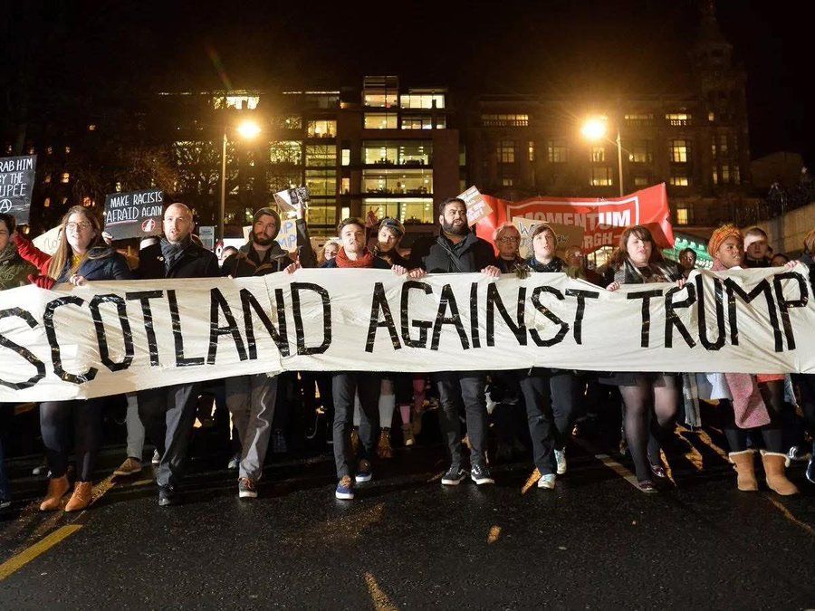 Mass protests against Donald Trump, line of protestors hold sign that says “Scotland against Trump”