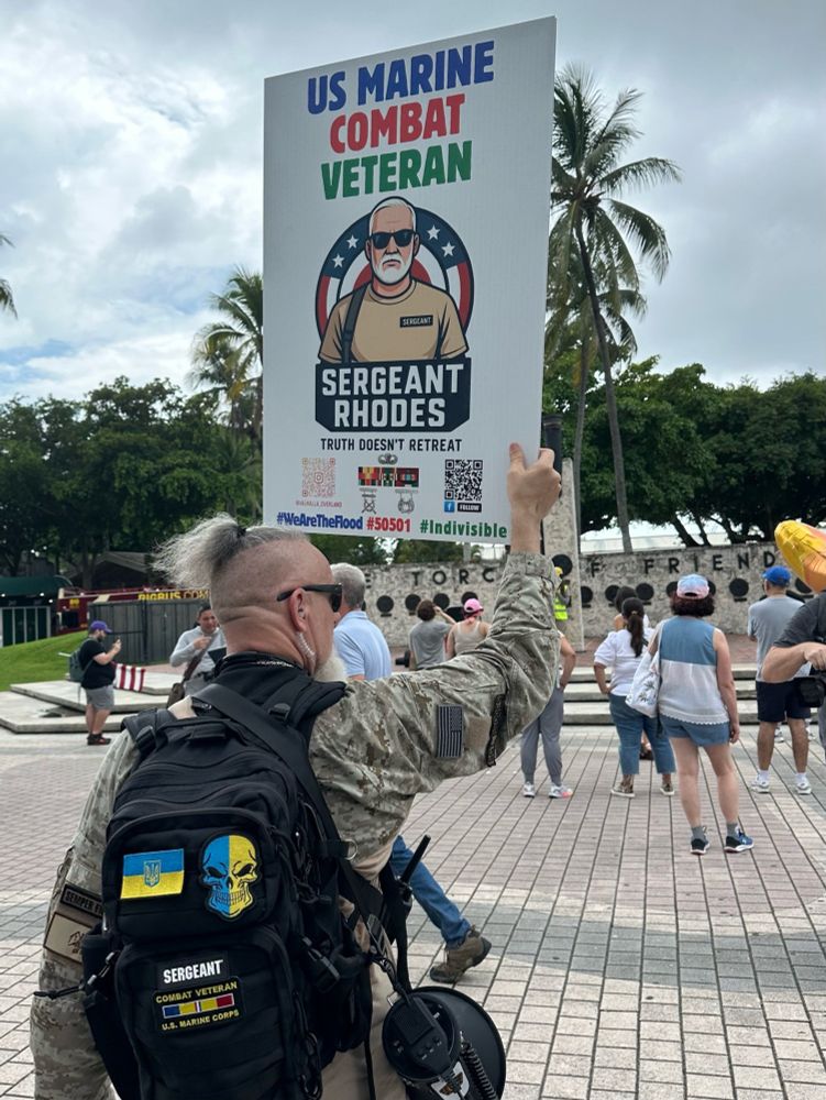 US combat veteran shows support for Ukraine with patches on his backpack, holds sign that reads 