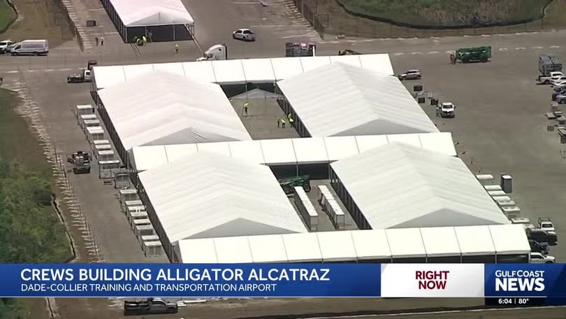 Aerial view of workers constructing large white tents at Dade-Collier Training and Transportation Airport for the Alligator Alcatraz project.