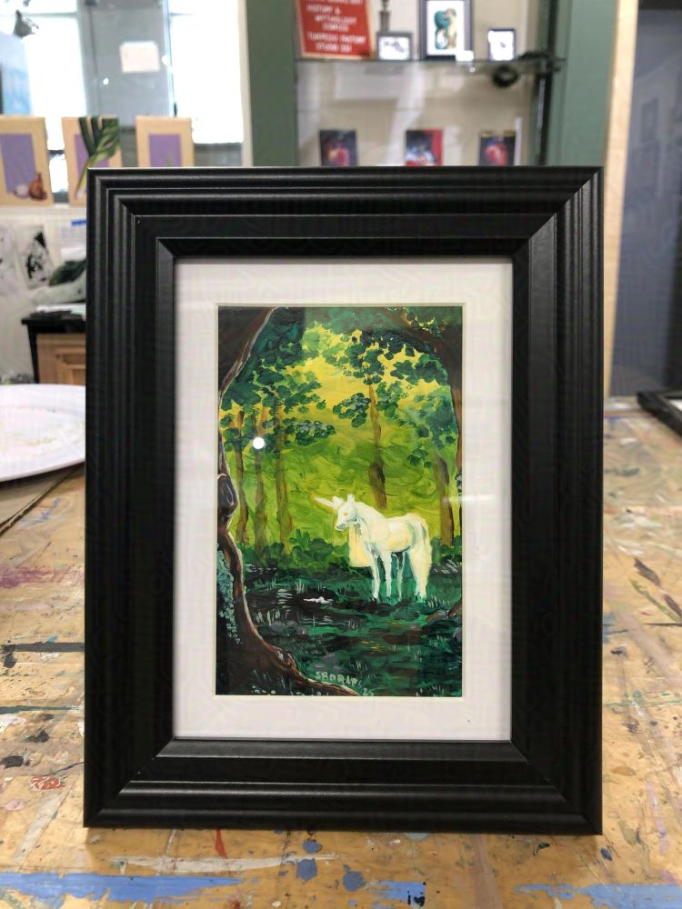 A small acrylic painting of a unicorn in a forest glen, looking at its reflection in a pool of dark water. Yellow sunlight dapples the forest floor and the unicorn's white coat.