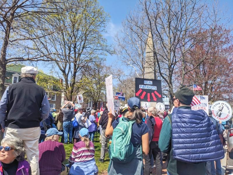 Crowd with signs and flags in Monument Square, Concord MA on April 21, 2025