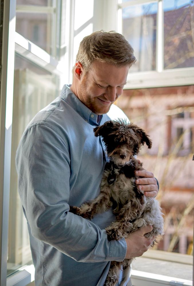 Tobias Raab in seinem Büro mit seinem Hund Elsa, einem amerikanischen Zwergschnauzer, auf dem Arm.