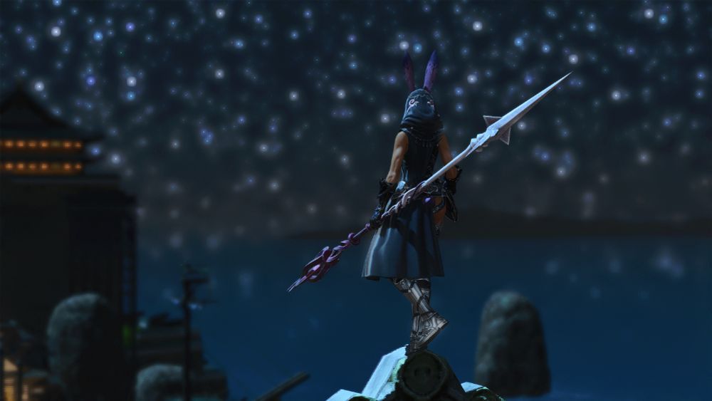 Kit Hareington, in drapey deep blue and silver armor with magenta accents, perches atop a tall building in Kugane, holding a massively long purple spear. She looks out over the harbor, a field of stars, and buildings in the landscape before her.