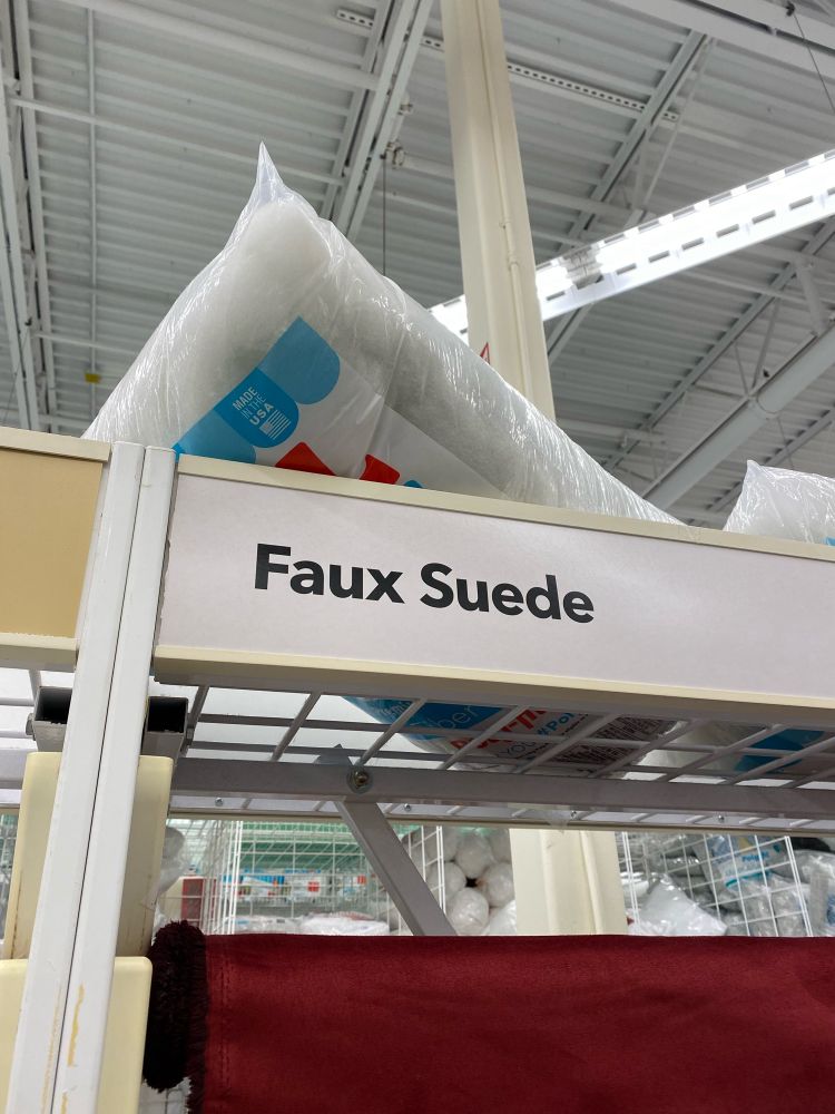 A shelf of fabric with the label “Faux Suede”