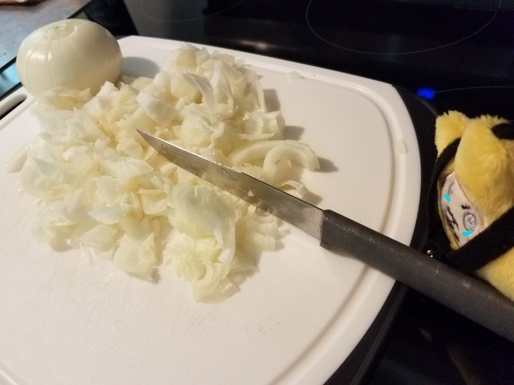 Starzzy has haphazardly chopped the first onion on the cutting board. The fumes from the onion made tears form under his eyes. 