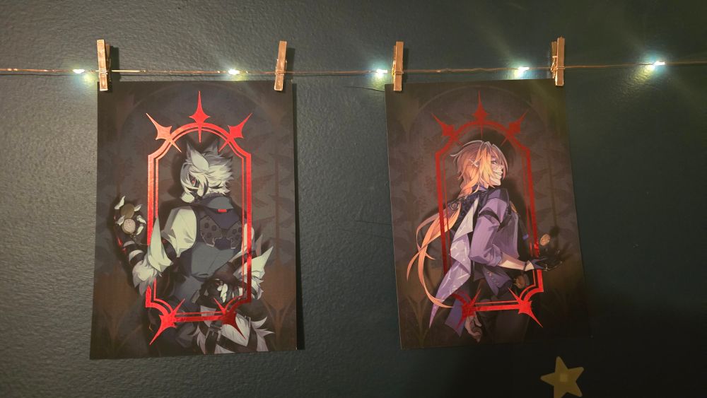 Two prints from zetallis.com one of Von Lycon and the other of Hugo Vlad. Both from the game Zenless Zone Zero. Lycaon is glancing over his shoulder with an open pocket watch in his hand. Hugo is glancing over his shoulder while flipping a coin. Both prints have shiny red foil designs framing the characters.