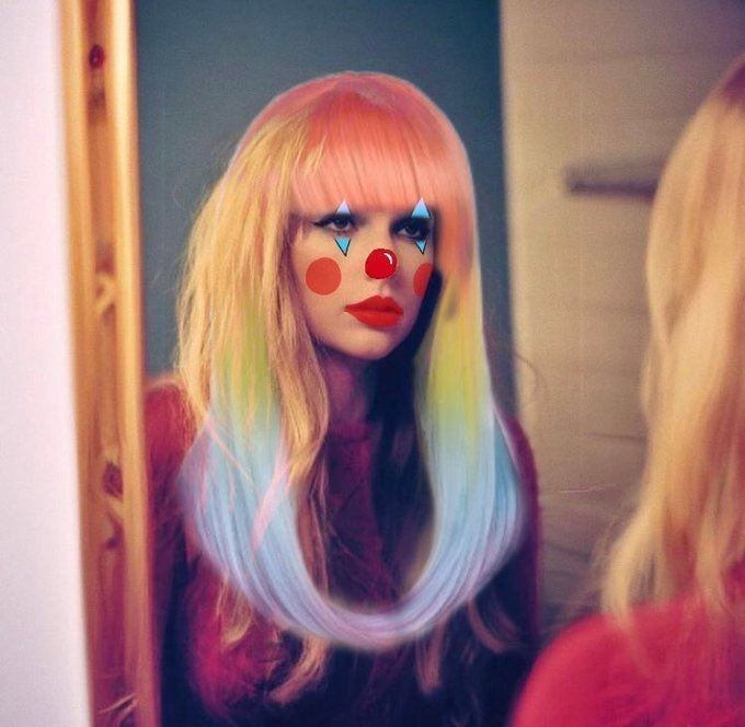 Taylor Swift looking into a mirror with clown makeup edited onto her and edited rainbow hair