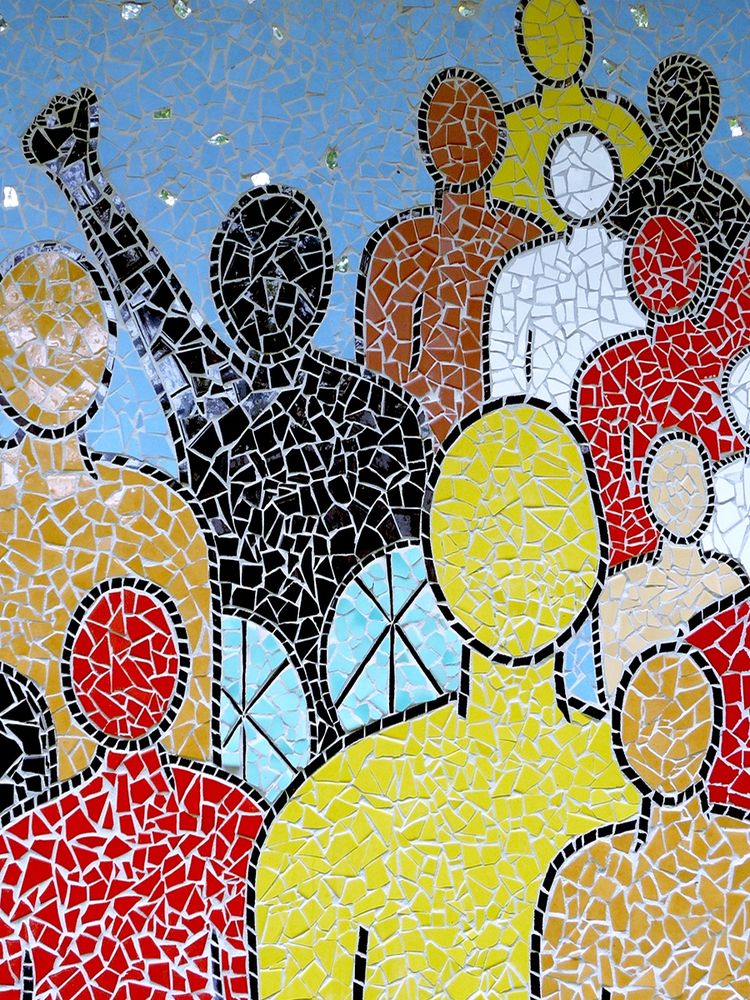 Tile mosaic of human-shaped figures of various colours. A figure composed of black tiles has their fist raised above their head. 