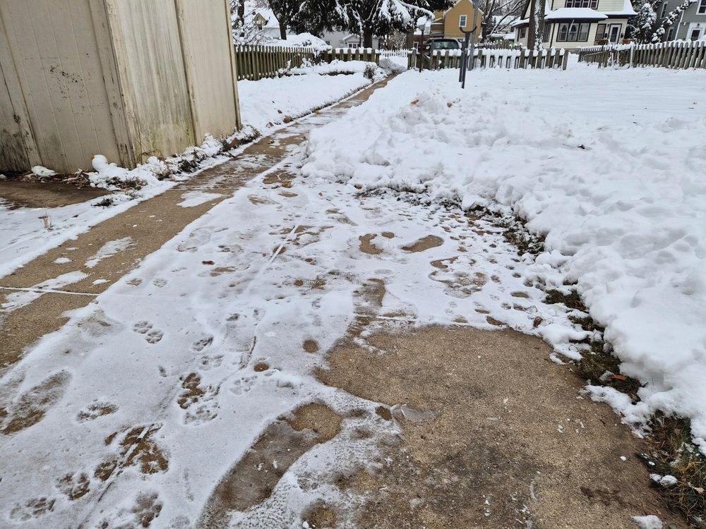 A concrete patio with some areas where snow either was removed or melted, and some areas with a light dusting of snow