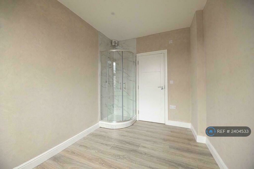 Une pièce vide avec une cabine de douche. La porte d'entrée est fermée mais on voit qu'elle bute contre la cabine une fois ouverte.