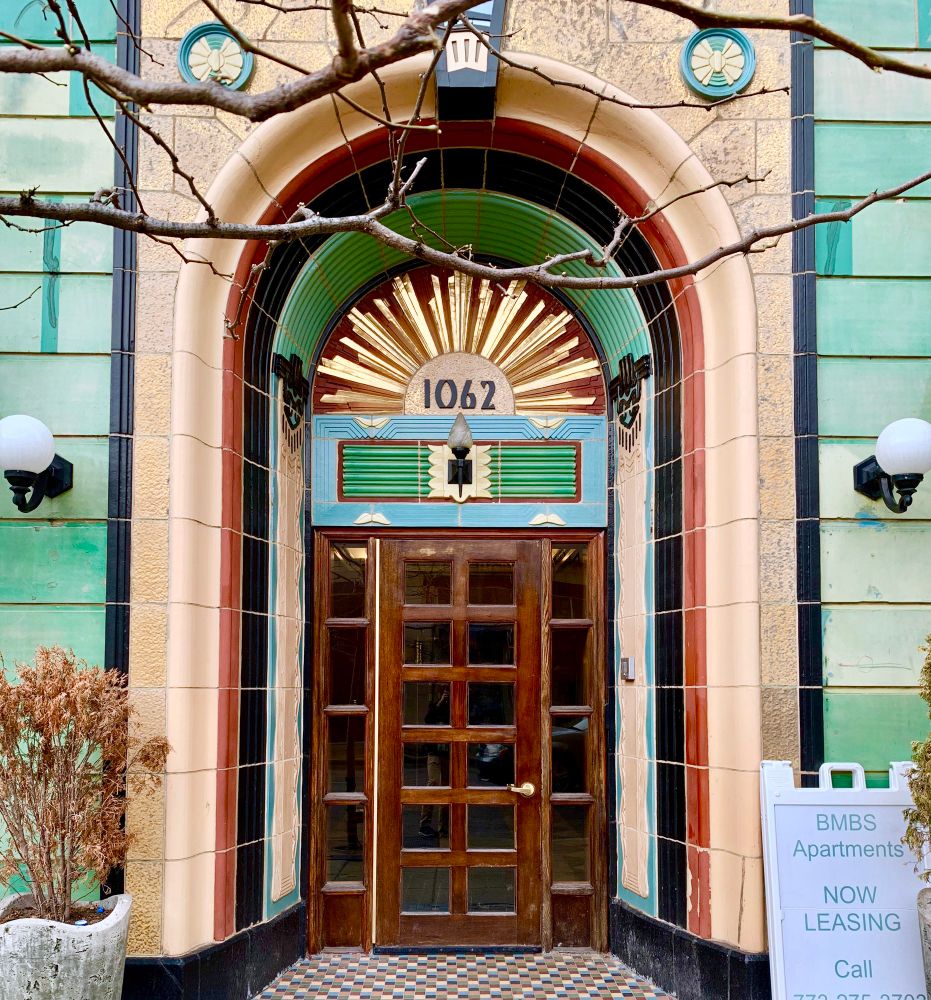 A colorful terra cotta entrance to a vintage apartment building in the art deco style. 