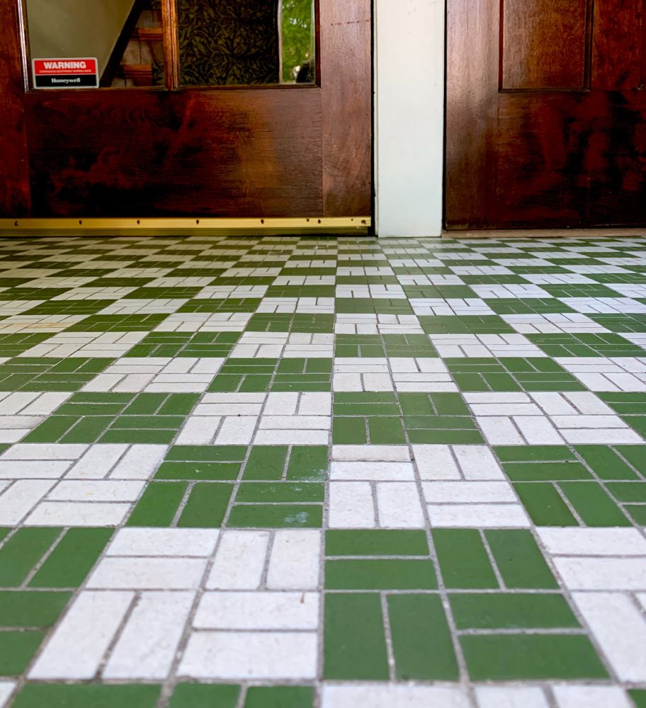 A green and white checkered vintage tile floor and the bottoms of two vintage wood doors.