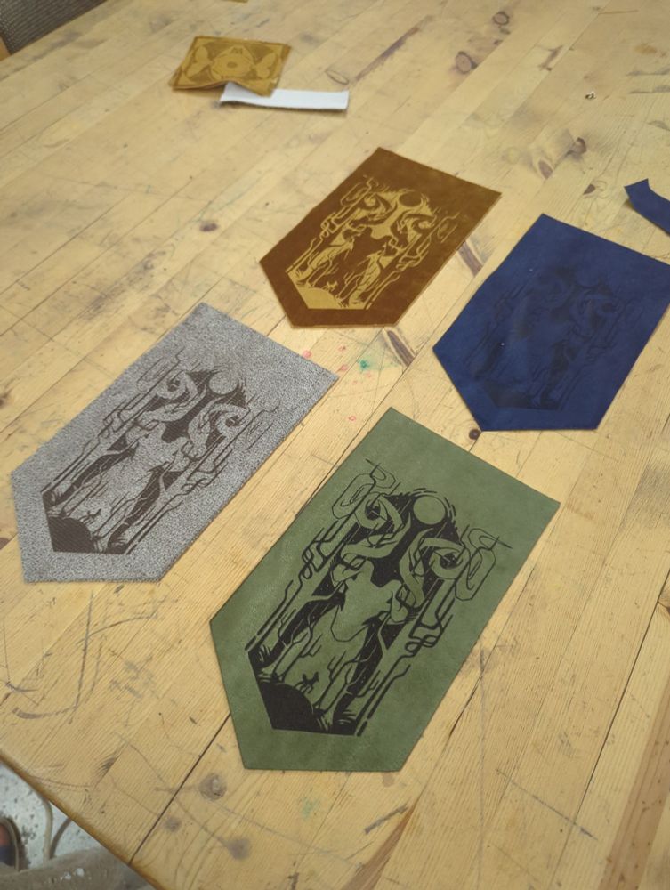 a photo of different types of engraved velvet banners, showcasing a gold, blue, silver and green velvet fabric with an abstract deer design engraved into the fabric pile.