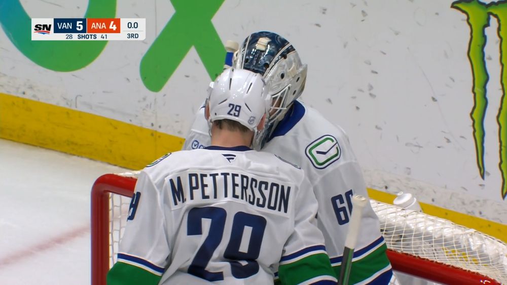 Canucks goaltender Nikita Tolopilo getting a helmet bump from defenseman Marcus Pettersson after the win