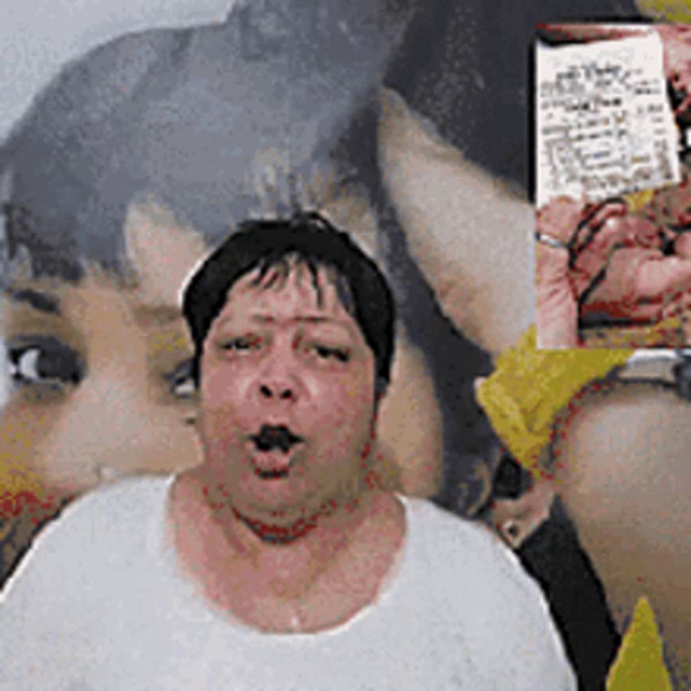 a woman in a white shirt is making a funny face in front of a picture of a woman 's face