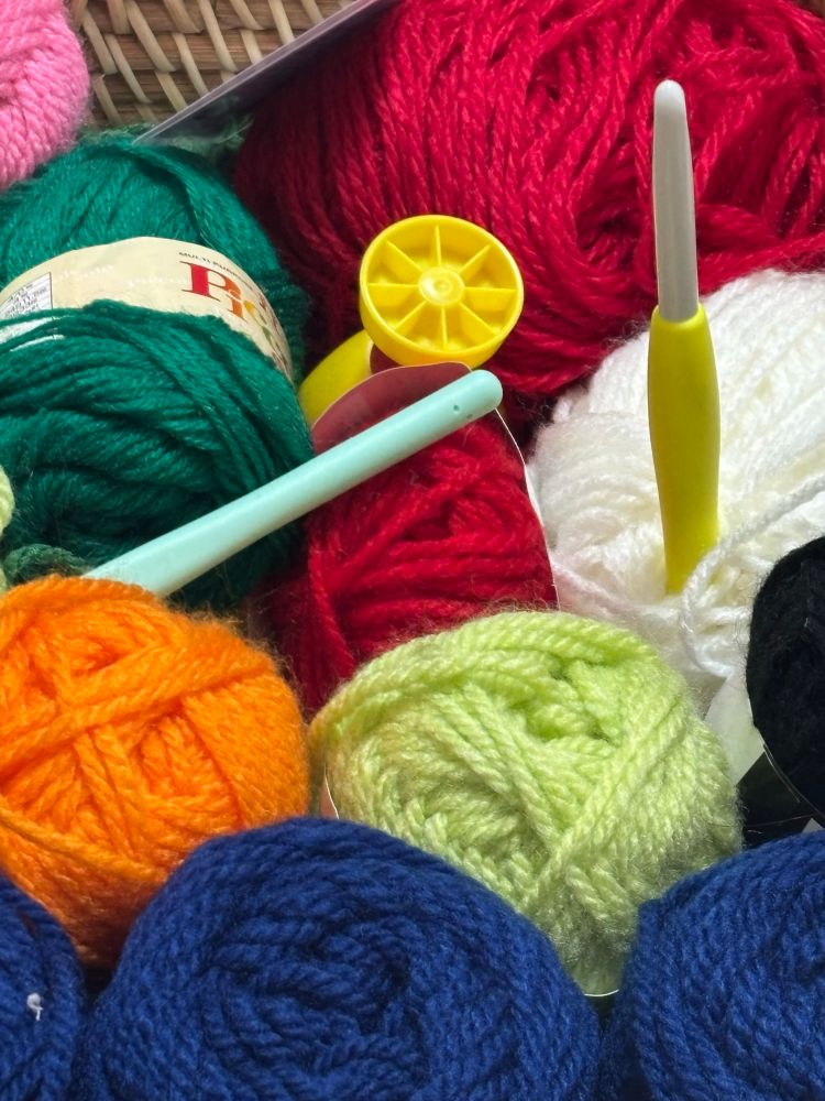 色々な色の毛糸玉にかぎ針が2本刺さっている様子