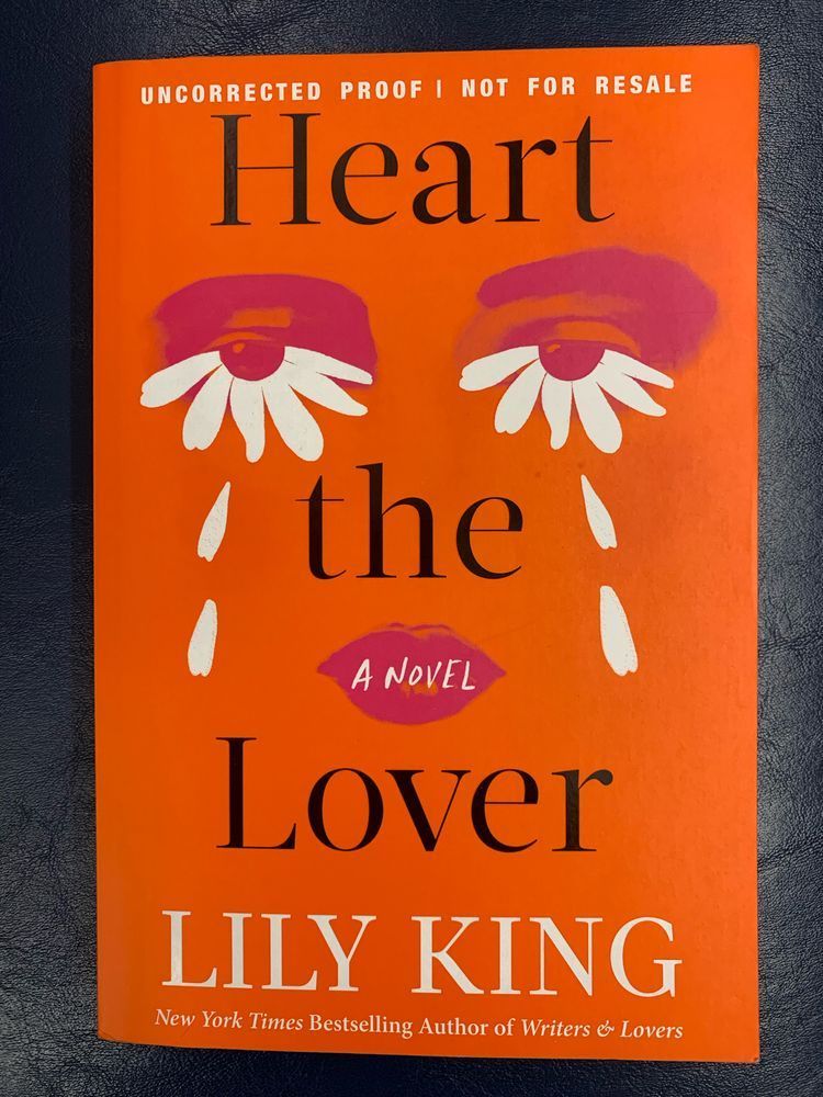 book cover for heart the liver by lily king with black lettering over a bright orange cover featuring eyes and lips in pink with white petals bordering the lower half of both eyes and below, evoking daisy flowers and tears