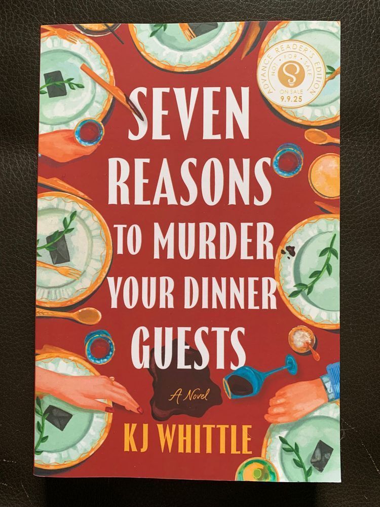 book cover for seven reasons to murder your dinner guests by kj whittle with white lettering over a cartoon image of an overhead view of a table set with a red tablecloth and gold rimmed plates with springs of greenery visible on them. the hands of guests, some cutlery, a few wineglasses, and a salt cellar are visible
