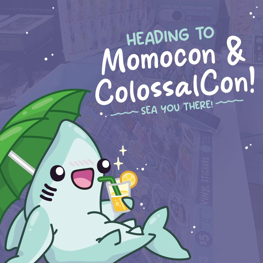 A cute teal shark lounges under a green beach umbrella, sipping a drink with a lemon slice. Behind it is a greyed-out photo of an artist convention table with stickers & charms. Text on the image reads 'Heading to Momocon & Colossalcon! Sea You There!"