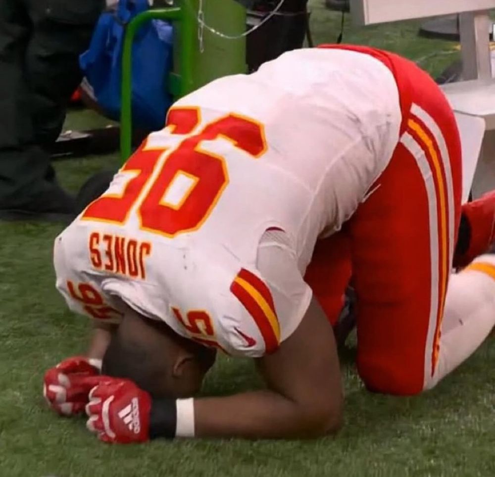 Chris Jones kneeling on the ground with his head down 