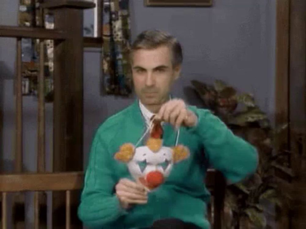 a man in a green sweater is sitting in a chair holding a stuffed clown .