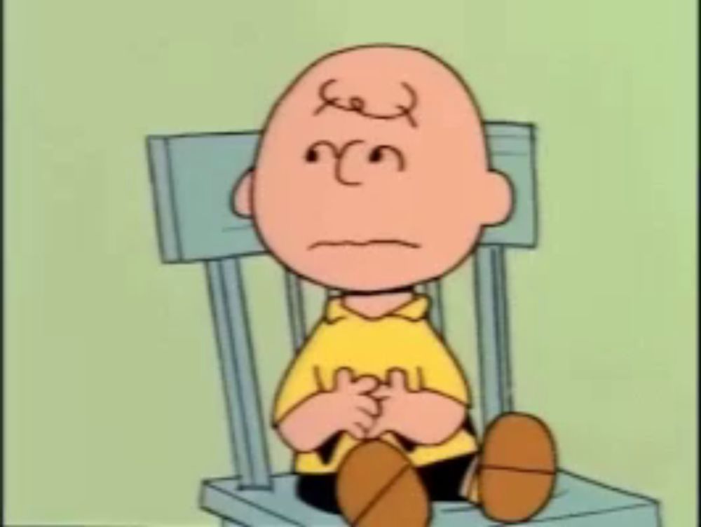 charlie brown is sitting in a chair with his eyes closed