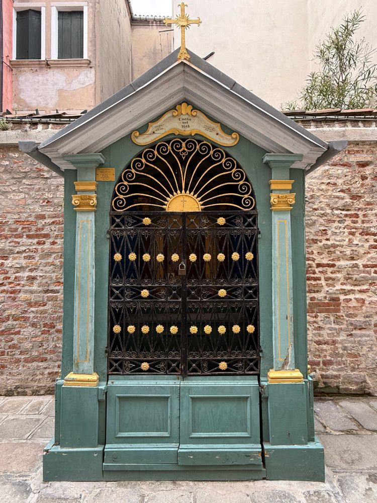 A wooden wee building with deep and lighter green accented with gilt.