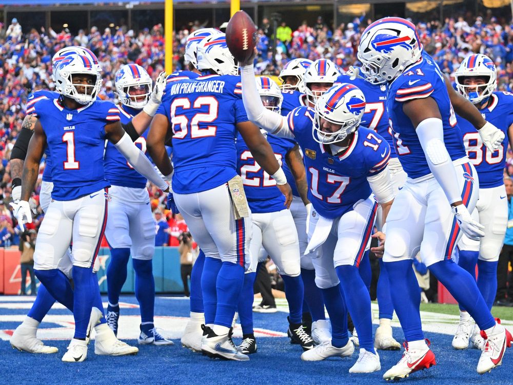 Football team with blue jerseys, white pants and white helmets. #17 is spiking a football