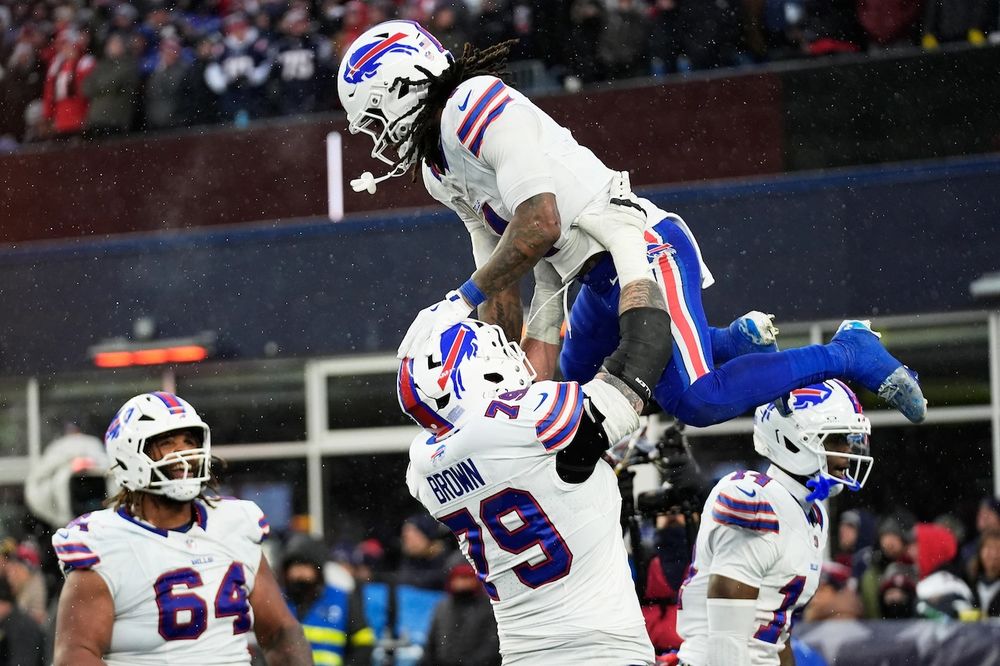 One buffalo bills player holding another buffalo bills player in celebration. 