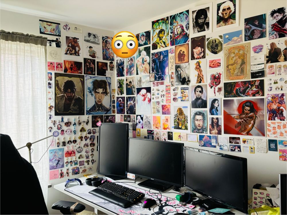 Photo of my computer setup at home, with three screens and the walls covered in fanart