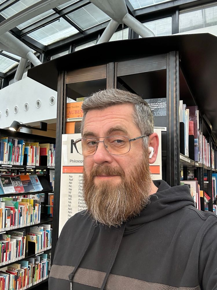 Selfie vor den Bücherregal einer Bibliothek. 