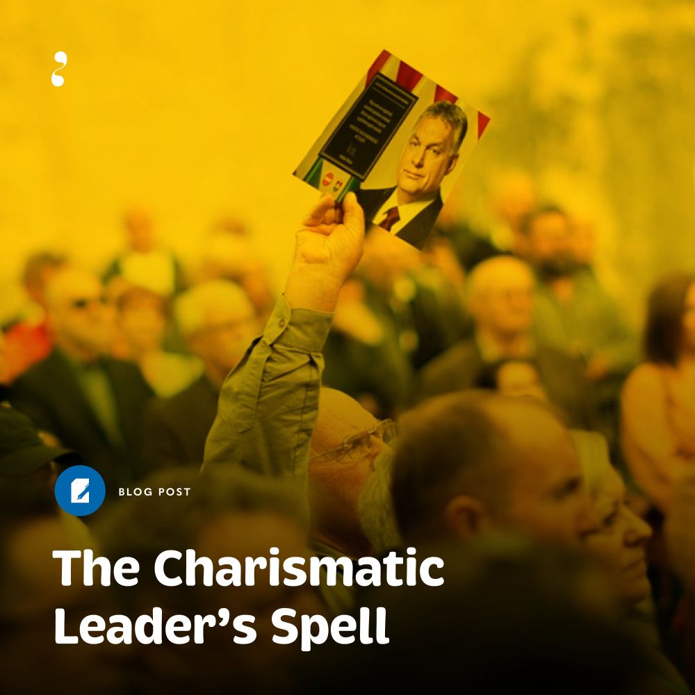 A person in a crowd holds up a booklet featuring a portrait of Viktor Orbán against a backdrop of blurred spectators. The image has a yellow overlay, and the text overlay reads "The Charismatic Leader’s Spell," indicating a blog post about political charisma and leadership influence. Photo credit: Social media reproduction.